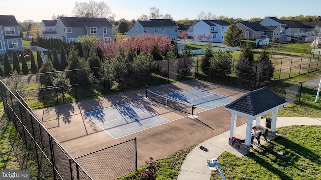 view of tennis court featuring a residential view and fence