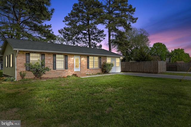 ranch-style house featuring fence, a front yard, and brick siding