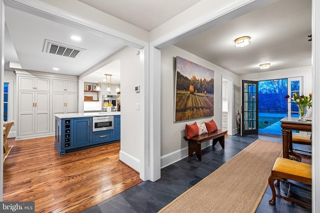 hall with dark wood-style flooring, recessed lighting, visible vents, and baseboards