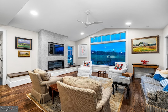 living area with baseboards, ceiling fan, wood finished floors, a large fireplace, and lofted ceiling