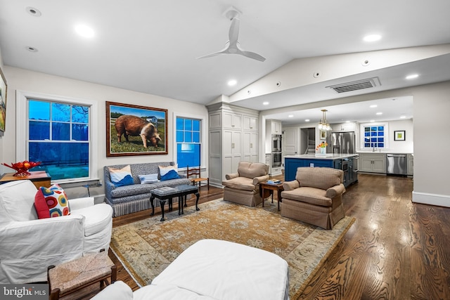 living room featuring dark wood-type flooring, vaulted ceiling, visible vents, and recessed lighting