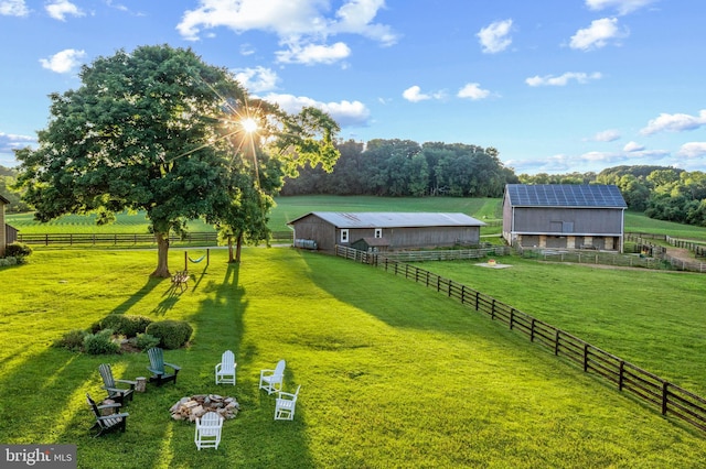 view of yard with a rural view, an outbuilding, fence, and a pole building