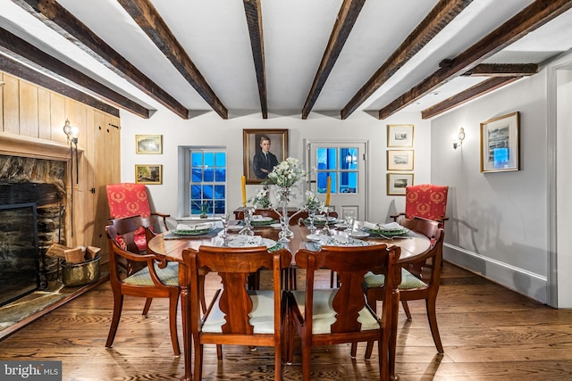 dining space featuring beam ceiling, wood finished floors, and a fireplace