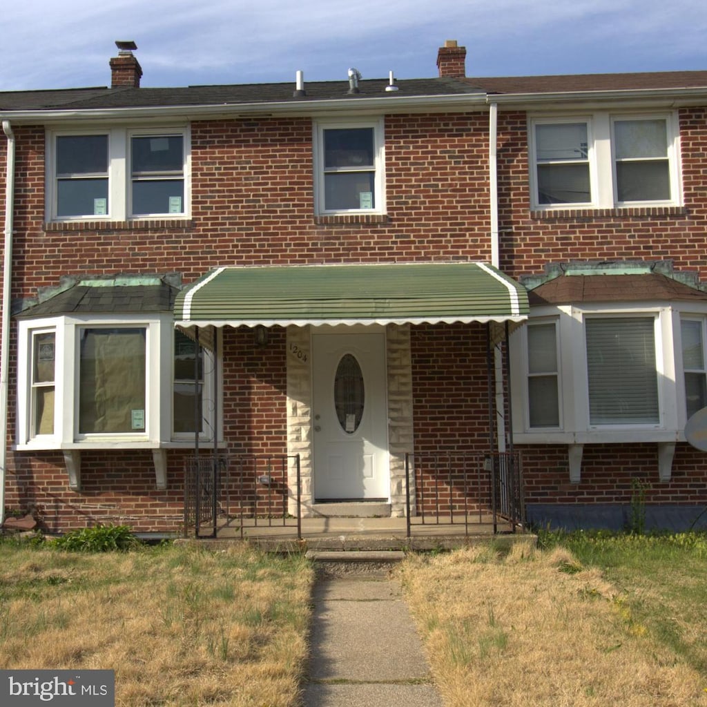 multi unit property with brick siding, a front lawn, and a chimney
