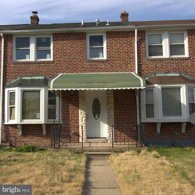 multi unit property with brick siding, a front lawn, and a chimney