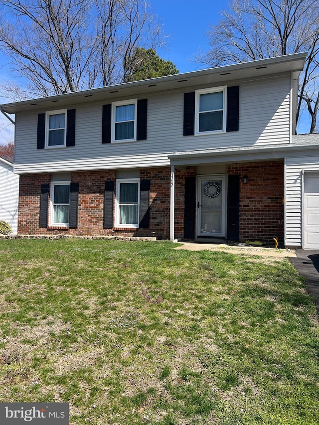 view of front of home with a front lawn, brick siding, and an attached garage