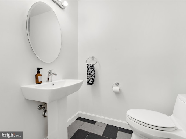 half bathroom featuring baseboards and toilet