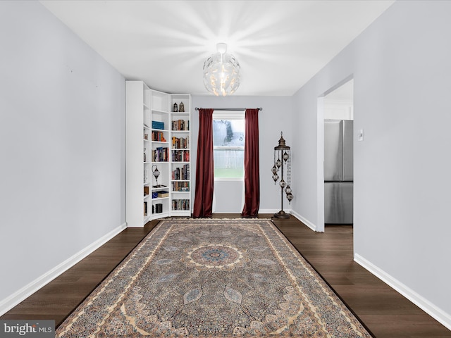 foyer entrance featuring wood finished floors, baseboards, and a chandelier