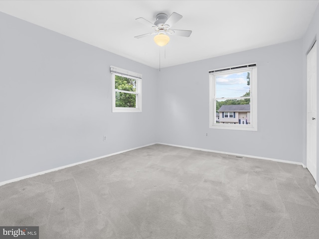 carpeted spare room featuring baseboards and a ceiling fan
