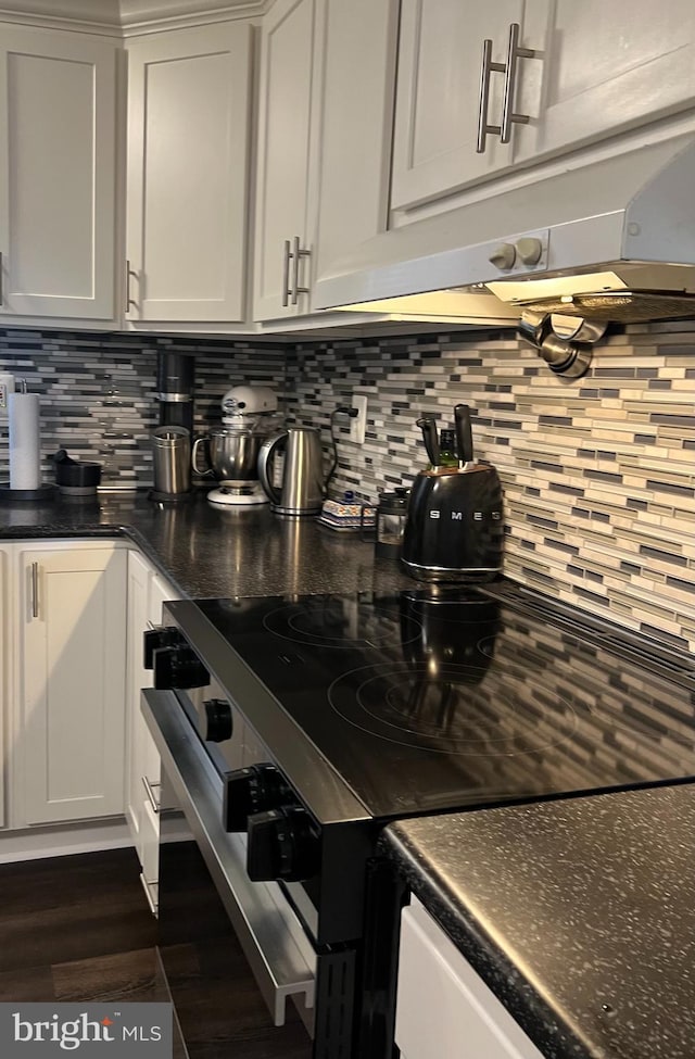 kitchen featuring range with electric cooktop, tasteful backsplash, dark wood finished floors, and dark countertops