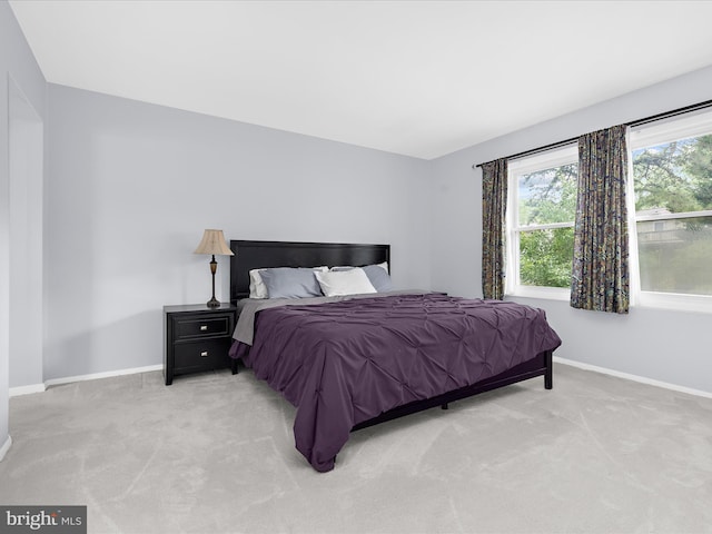 bedroom with baseboards and light colored carpet
