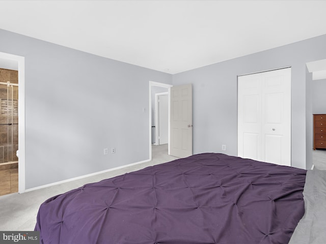 carpeted bedroom featuring a closet, baseboards, and ensuite bath