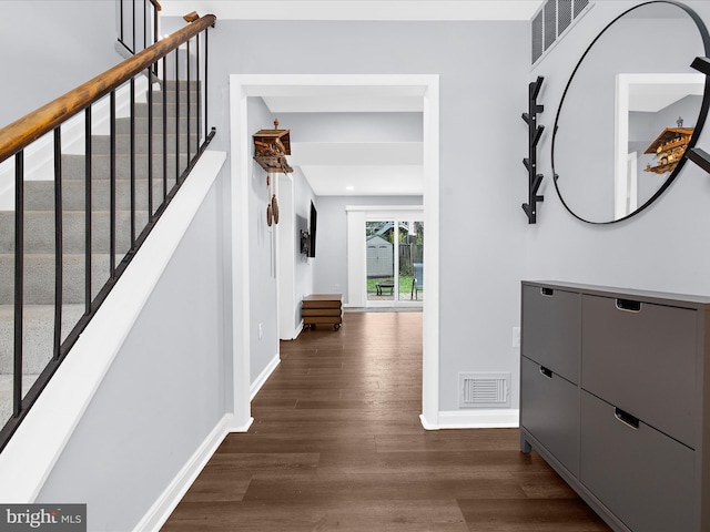 hallway with dark wood-style floors, baseboards, and stairway