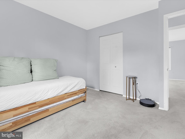 carpeted bedroom featuring baseboards and a closet