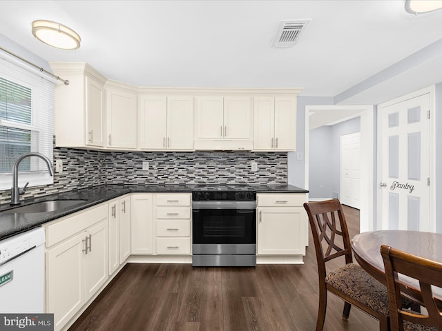 kitchen with electric range, dishwasher, a sink, dark wood finished floors, and dark countertops