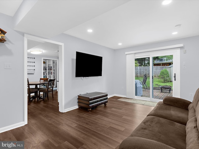 living room featuring dark wood-type flooring, baseboards, and recessed lighting