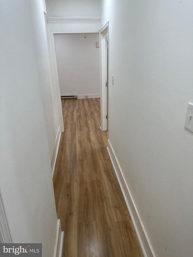 hallway featuring wood finished floors, baseboards, and a baseboard radiator