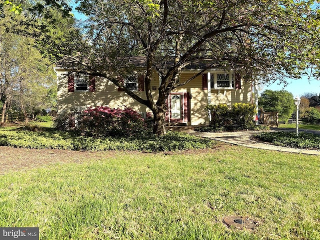 view of property hidden behind natural elements featuring a front lawn