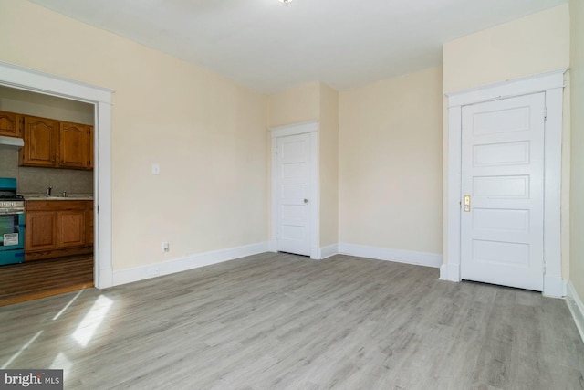 2607 Quantico Ave, Baltimore, MD 21215 - unfurnished living room featuring light wood-type flooring, a sink, and baseboards