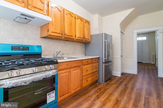 2607 Quantico Ave, Baltimore, MD 21215 - kitchen with a sink, radiator heating unit, stainless steel appliances, decorative backsplash, and under cabinet range hood