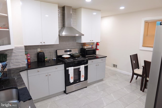 kitchen with wall chimney range hood, stainless steel appliances, white cabinets, and dark countertops