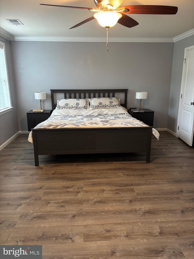 bedroom featuring crown molding, wood finished floors, visible vents, and baseboards