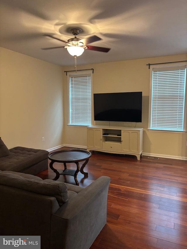 living area with baseboards, dark wood-style flooring, ceiling fan, and plenty of natural light