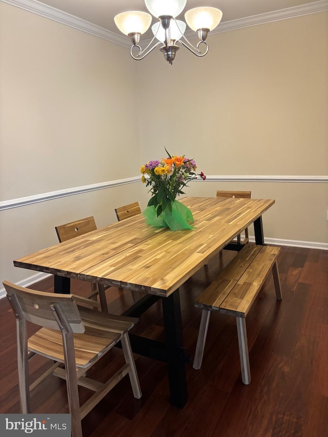 dining area with dark wood-style flooring, ornamental molding, a notable chandelier, and baseboards