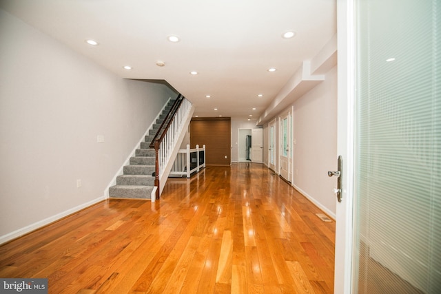 interior space with light wood finished floors, baseboards, recessed lighting, and stairway