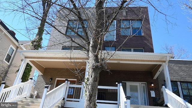 exterior space with a porch and brick siding
