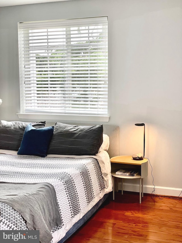 bedroom featuring multiple windows, wood finished floors, and baseboards