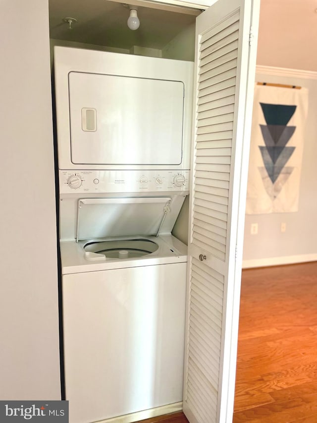 laundry room with baseboards, laundry area, and stacked washer / drying machine