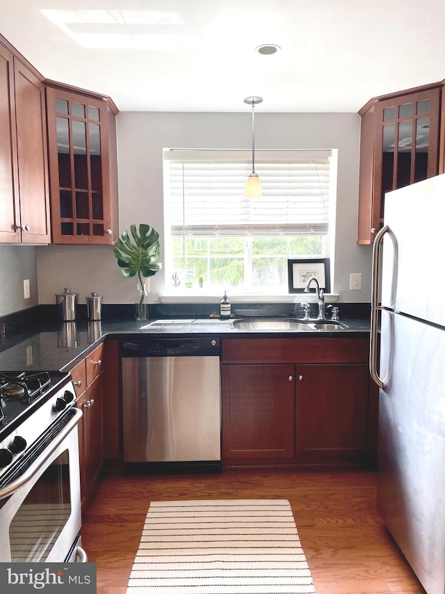 kitchen featuring a sink, stainless steel appliances, pendant lighting, and dark wood-type flooring