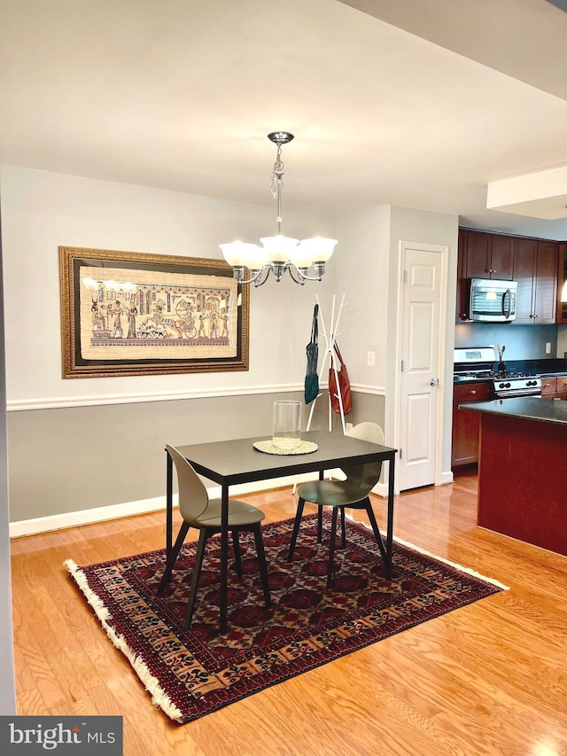 dining room featuring baseboards, a notable chandelier, and wood finished floors