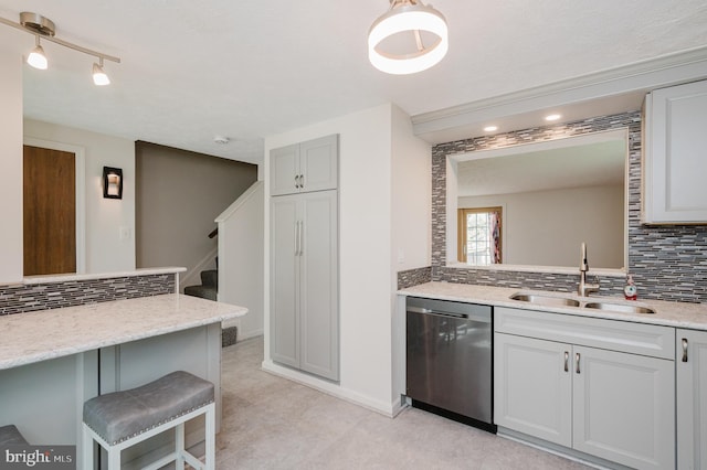 kitchen featuring backsplash, dishwasher, a breakfast bar area, and a sink
