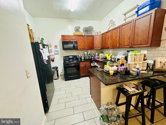 kitchen with tasteful backsplash, a breakfast bar, a peninsula, black appliances, and a sink