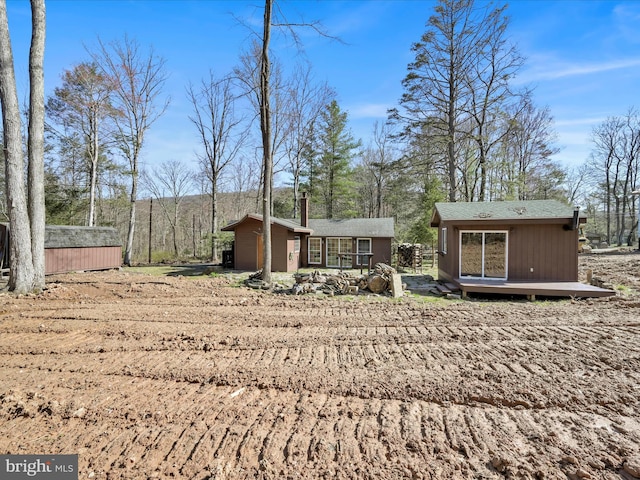 back of property featuring an outdoor structure and a wooden deck