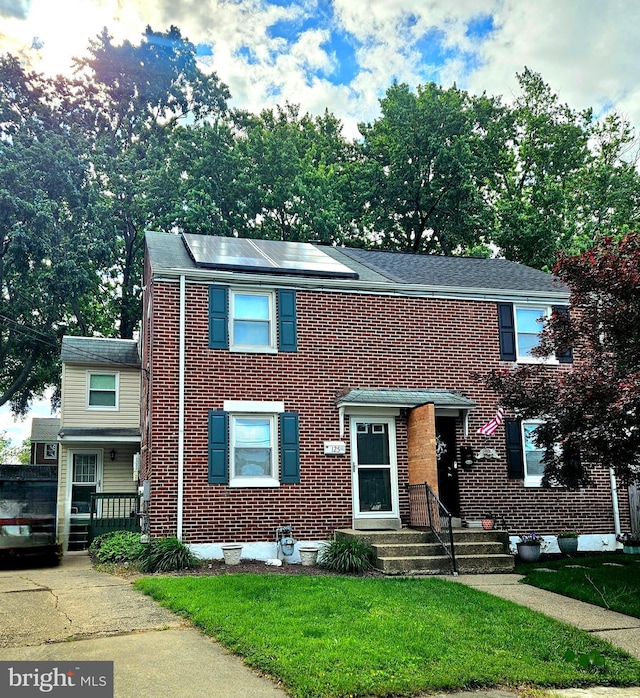125 Denn Pl, Wilmington, DE 19804 - view of front facade featuring brick siding, a front lawn, and roof mounted solar panels