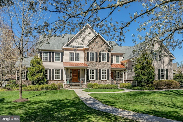 view of front of house with a front lawn, stone siding, and a standing seam roof