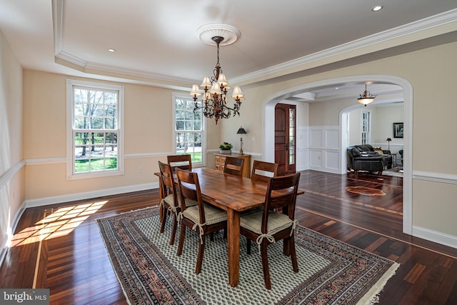 dining room featuring dark wood-style flooring, arched walkways, a notable chandelier, and crown molding