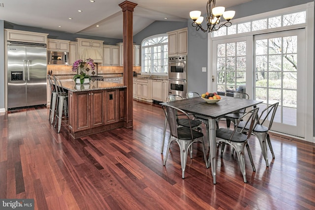 dining space featuring decorative columns, dark wood finished floors, vaulted ceiling, recessed lighting, and a chandelier