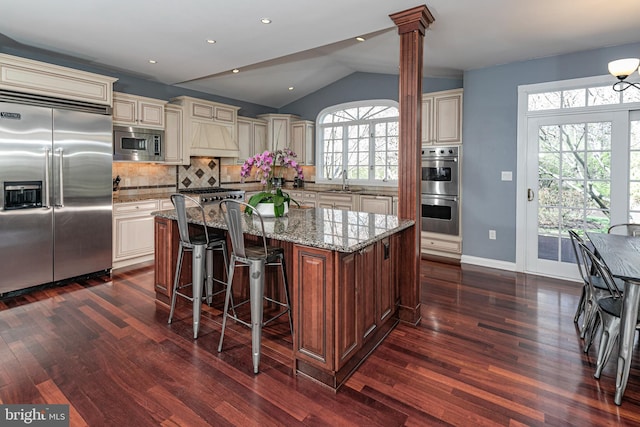 kitchen featuring dark wood-type flooring, built in appliances, a sink, and cream cabinetry