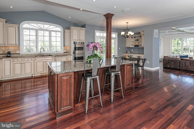 kitchen featuring a notable chandelier, dark wood-style flooring, a sink, double oven, and cream cabinets