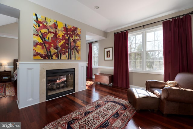 living area with baseboards, a glass covered fireplace, and wood finished floors
