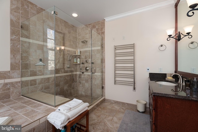 bathroom featuring baseboards, crown molding, a shower stall, radiator, and vanity