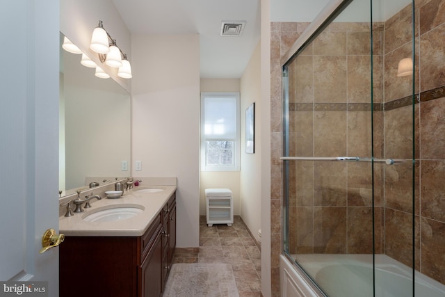 bathroom with shower / bath combination with glass door, double vanity, visible vents, and a sink