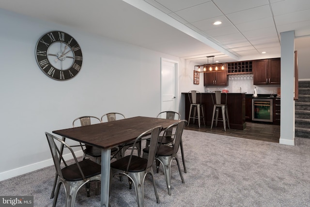dining room featuring wine cooler, carpet, wet bar, and baseboards
