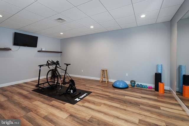 exercise room featuring a paneled ceiling, visible vents, recessed lighting, wood finished floors, and baseboards