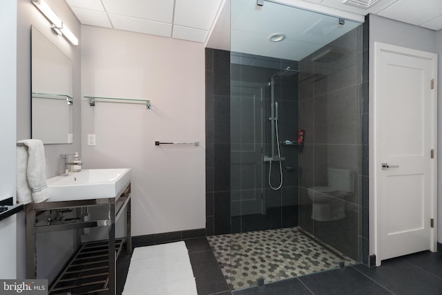 bathroom with a sink, baseboards, a walk in shower, and tile patterned flooring