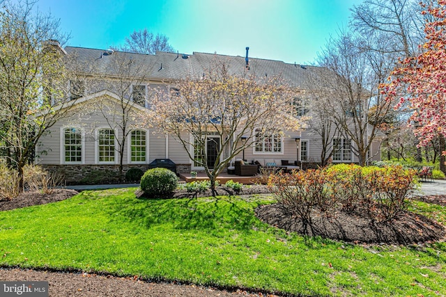 back of property featuring a yard, an outdoor living space, stone siding, and a patio area